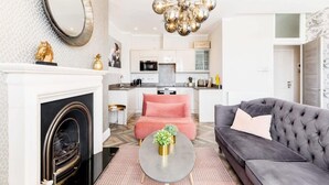 Ein modernes Wohnzimmer mit Kamin, einem grauen Sofa, einem rosafarbenen Sessel und einem runden Couchtisch.