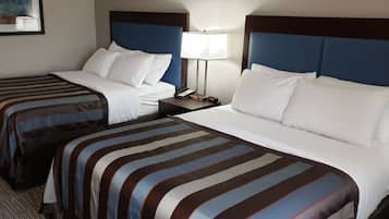 Ein Hotelzimmer mit zwei Betten, jeweils mit gestreifter Bettwäsche und weißen Kissen. Ein Nachttisch mit Lampe und Telefon ist ebenfalls vorhanden.