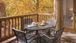 A round table with chairs on a wooden deck, overlooking a forest with autumn foliage. - Wyndham Resort at Fairfield Mountains (Lake Lure)
