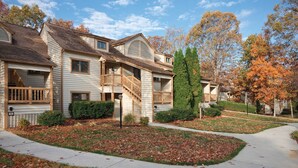 A two-story residential building with a covered front porch, a staircase leading to the upper floor, and a well-maintained lawn with fallen leaves. - Wyndham Resort at Fairfield Mountains (Lake Lure)
