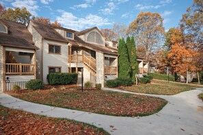 A two-story residential building with a covered front porch, a staircase leading to the upper floor, and a well-maintained lawn with fallen leaves. - Wyndham Resort at Fairfield Mountains (Lake Lure)
