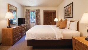 Habitación de hotel con una cama grande, muebles de madera, un televisor y un cuadro en la pared.