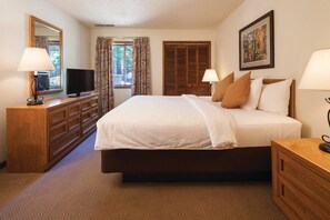 A hotel room with a large bed, wooden furniture, a television, and a painting on the wall. - Wyndham Resort at Fairfield Mountains (Lake Lure)