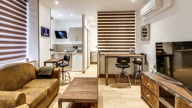 A modern kitchen with a dining area, a sofa, and a TV. - Le Vintage – Romantic Studio on Seine, Paris 6th (Paris)