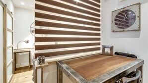 A dining area with a wooden table, metal frame, and a wall-mounted clock. - Le Vintage – Romantic Studio on Seine, Paris 6th (Paris)