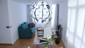 Een moderne woonkamer met een houten eettafel, een teal kleurige bank en een bijzondere sferische lamp.