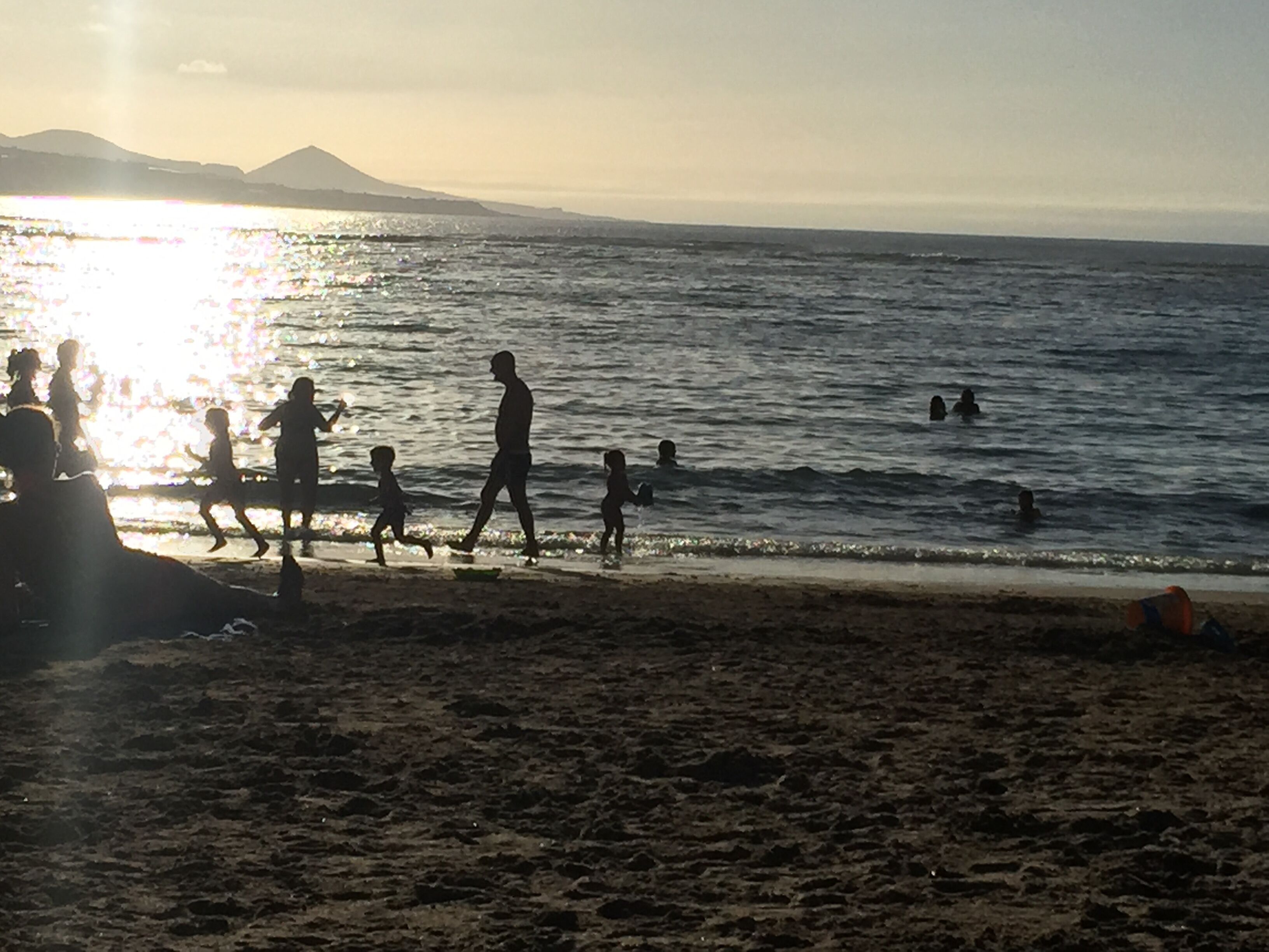 Une scène de plage où l’on voit des gens se promener et nager.