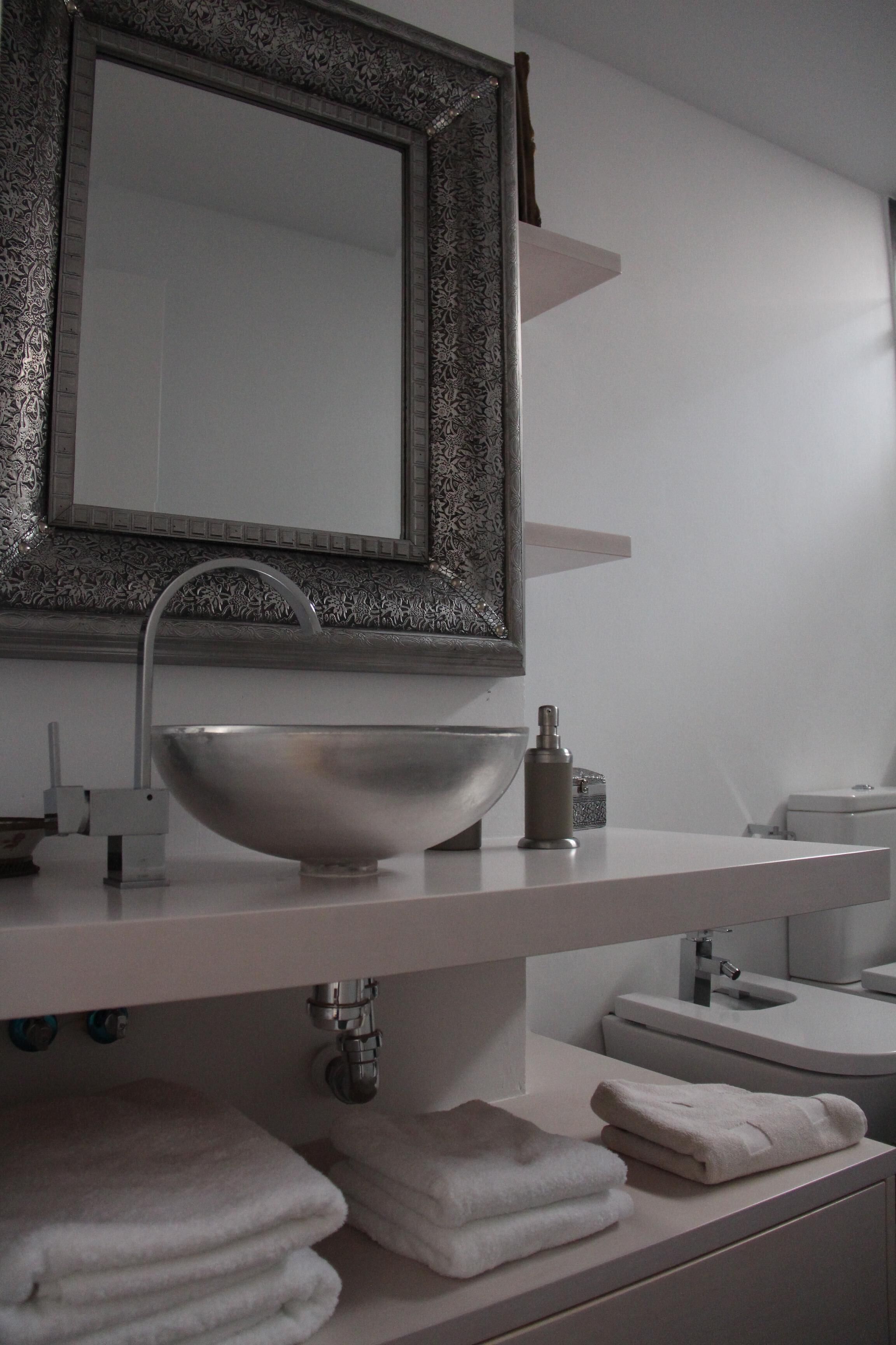 Un baño moderno con un espejo grande, un lavamanos sobre encimera y toallas ordenadamente dobladas.
