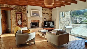 A cozy living room with a stone fireplace, leather sofas, and a TV.