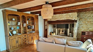 A cozy living room with a stone fireplace, a wooden bookcase, and a beige sofa.
