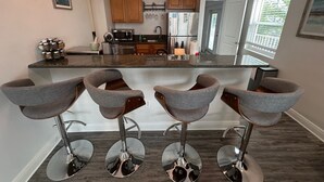 Una cocina moderna con una isla central, taburetes de bar, electrodomésticos de acero inoxidable e iluminación colgante.