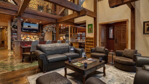 A spacious lounge area with leather sofas, a coffee table, and a bar area with a television. - Mega 10,000 sq.ft. Home w/ Hot Tub + Ski Shuttle - Rocking Chair Lodge (Steamboat Springs)