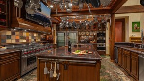A spacious kitchen with a large island, stainless steel appliances, hanging pots, and a variety of spices on the wall. - Mega 10,000 sq.ft. Home w/ Hot Tub + Ski Shuttle - Rocking Chair Lodge (Steamboat Springs)
