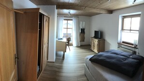 A bedroom with a bed, a desk, and a TV.