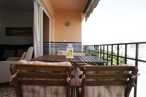 A balcony with wooden furniture, a table, and a sofa. - Imperial Apartment (Torremolinos)