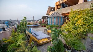 A rooftop with a wooden lounge chair, potted plants, and a small gazebo. - Hotel Pomelo House (Kathmandu)