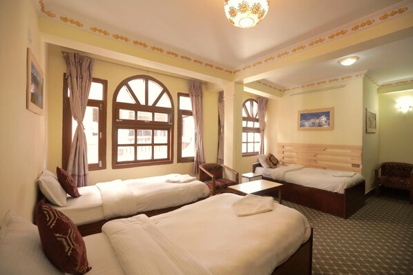A hotel room with two beds, a small table, a chair, and a sofa. - Hotel Pomelo House (Kathmandu)