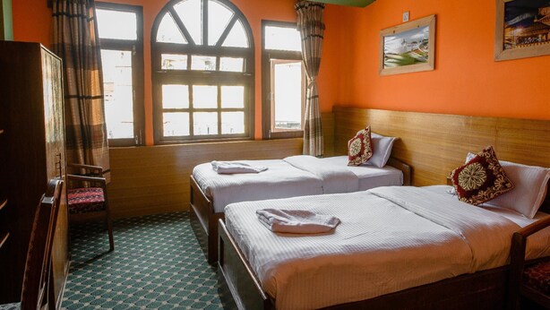 A room with two beds, a wooden headboard, a chair, and a window with curtains. - Hotel Pomelo House (Kathmandu)