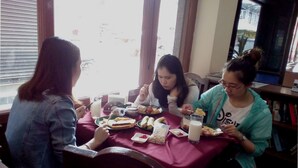Three people dining at a table with various food items and drinks. - Hotel Pomelo House (Kathmandu)