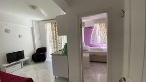 Une chambre d’hôtel avec un lit, un bureau avec un ordinateur, une télévision et une chaise.
