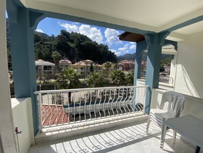 A balcony with a view of a residential area, a white chair, and a tiled floor. - Villa Eda Apart (Marmaris)