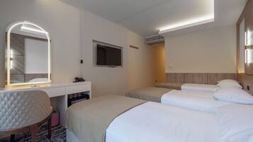 Une chambre d’hôtel comprenant un lit, un bureau avec un miroir, une télévision et un luminaire au plafond.