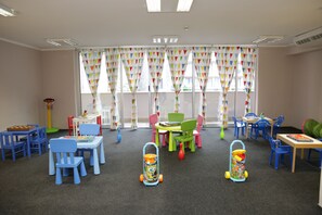 A children's playroom with colorful furniture, a play table, and two toy carts. - Hotel Tara (Bečići)