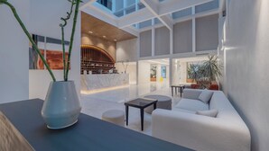 Un interior moderno con mostrador de recepción, zona de estar y un ventanal grande.