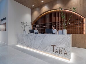 A hotel reception desk with a marble counter, a wooden panel wall, and a sign that reads 'Hotel Tara'. - Hotel Tara (Bečići)