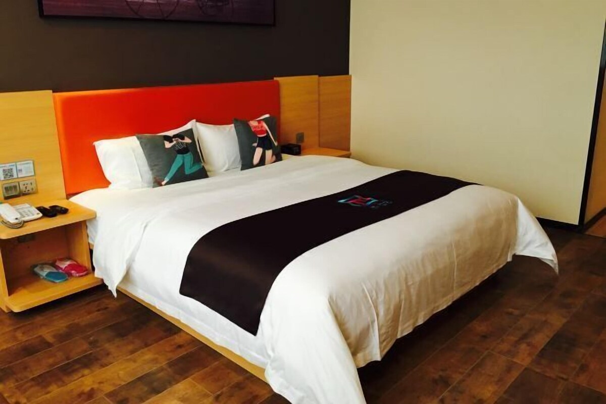 Ein Hotelzimmer mit Bett, Nachttisch und Holzboden.