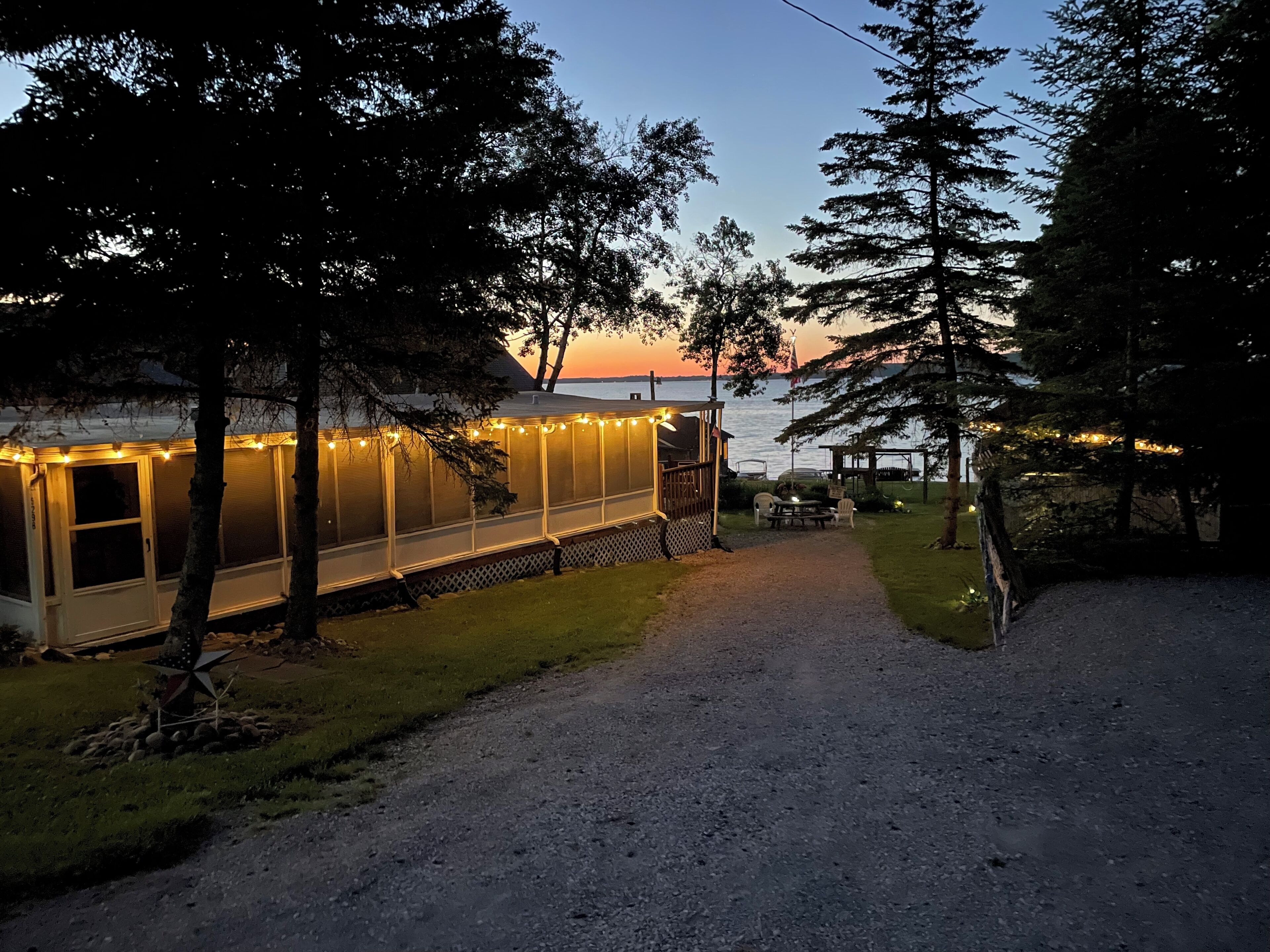 A covered outdoor area with string lights, a gravel path, and a view of the water.