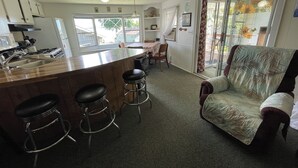 A kitchen with a bar area, bar stools, and a large window. - Vacation Stay at Hubbard Lake Air-Conditioned Lakefront Mobile Home (Hubbard Lake)