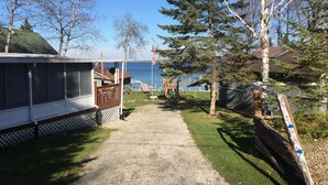 A gravel path leading to a wooden deck with a view of the water. - Vacation Stay at Hubbard Lake Air-Conditioned Lakefront Mobile Home (Hubbard Lake)