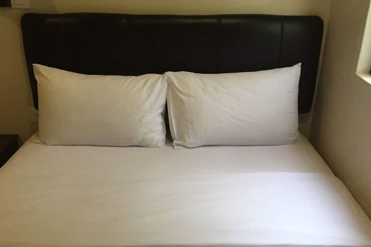 A bed with a black headboard and two white pillows.
