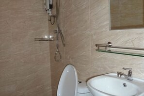 A bathroom with a white sink, a glass shelf, and a shower with a handheld showerhead. - Hotel Hong (Melaka)