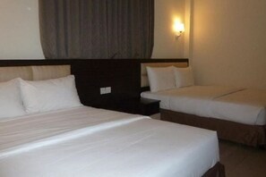 A hotel room with two beds, a nightstand, and a wall-mounted light. - Hotel Hong (Melaka)