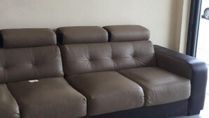 Ein braunes Ledersofa mit schwarzem Gestell in einem Zimmer mit einem großen Fenster.