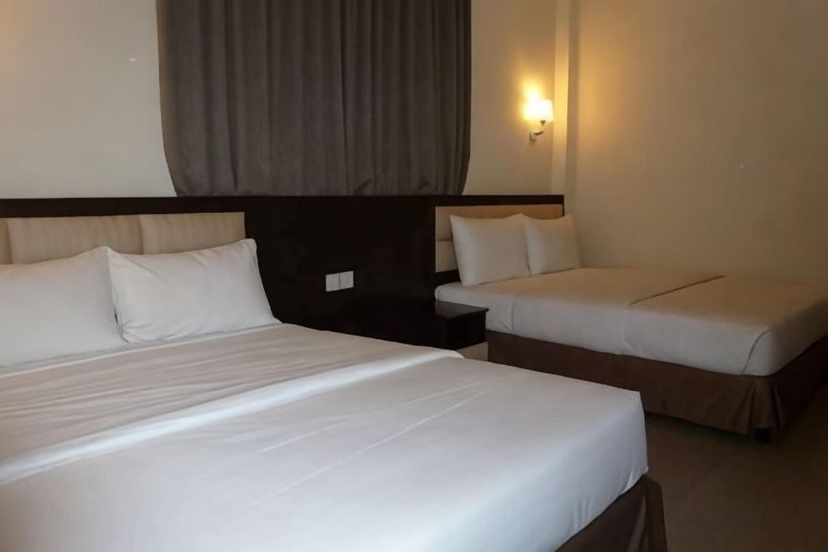 A hotel room with a large bed, a smaller bed, and a nightstand with a lamp.