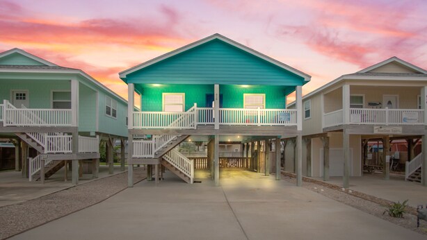 A row of beach houses with a central building featuring a balcony and a staircase leading to the upper level. - Boogie Board! Pet Friendly! Private Pool (Port Aransas)