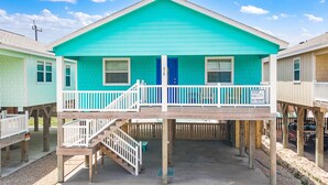 A turquoise two-story house with a balcony and a blue door. - Boogie Board! Pet Friendly! Private Pool (Port Aransas)
