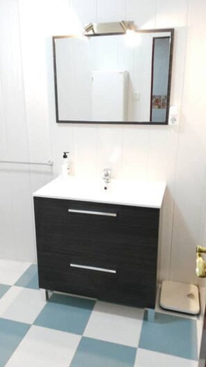 Een bad/douchecombinatie, een haardroger, handdoeken