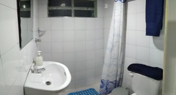 A small bathroom with a sink, toilet, and shower curtain.