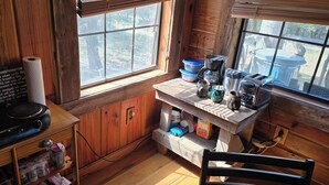 Una cocina rústica con paredes de madera, una ventana y una encimera con cafetera, tostadora y recipientes.