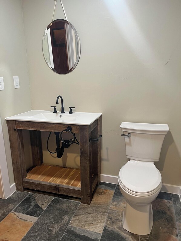 A bathroom with a white sink, dark wooden vanity, and a white toilet.