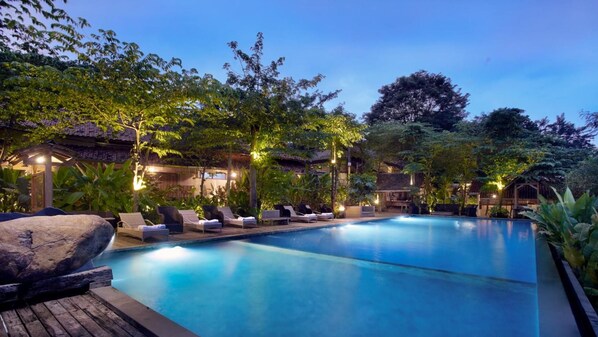 A swimming pool with lounge chairs and a gazebo in a landscaped garden at dusk. - Desa Alamanis Resort Vila (Beber)