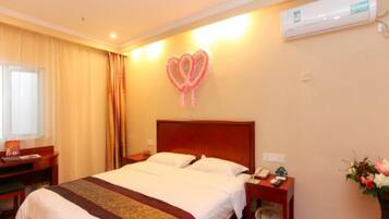 A hotel room with a bed, bedside tables, a desk, an air conditioner, and a wall decoration.