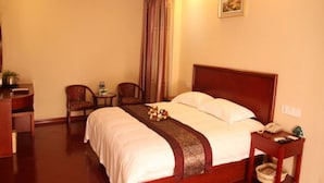 Una habitación de hotel con cama, mesita de noche, silla y escritorio con teléfono.