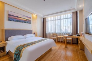 Une chambre d’hôtel avec un grand lit, un bureau, une chaise et une grande fenêtre avec des rideaux.