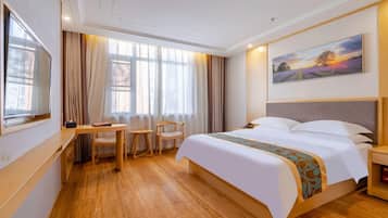 Una habitación de hotel con una cama grande, un escritorio con sillas, un televisor y un cuadro en la pared.