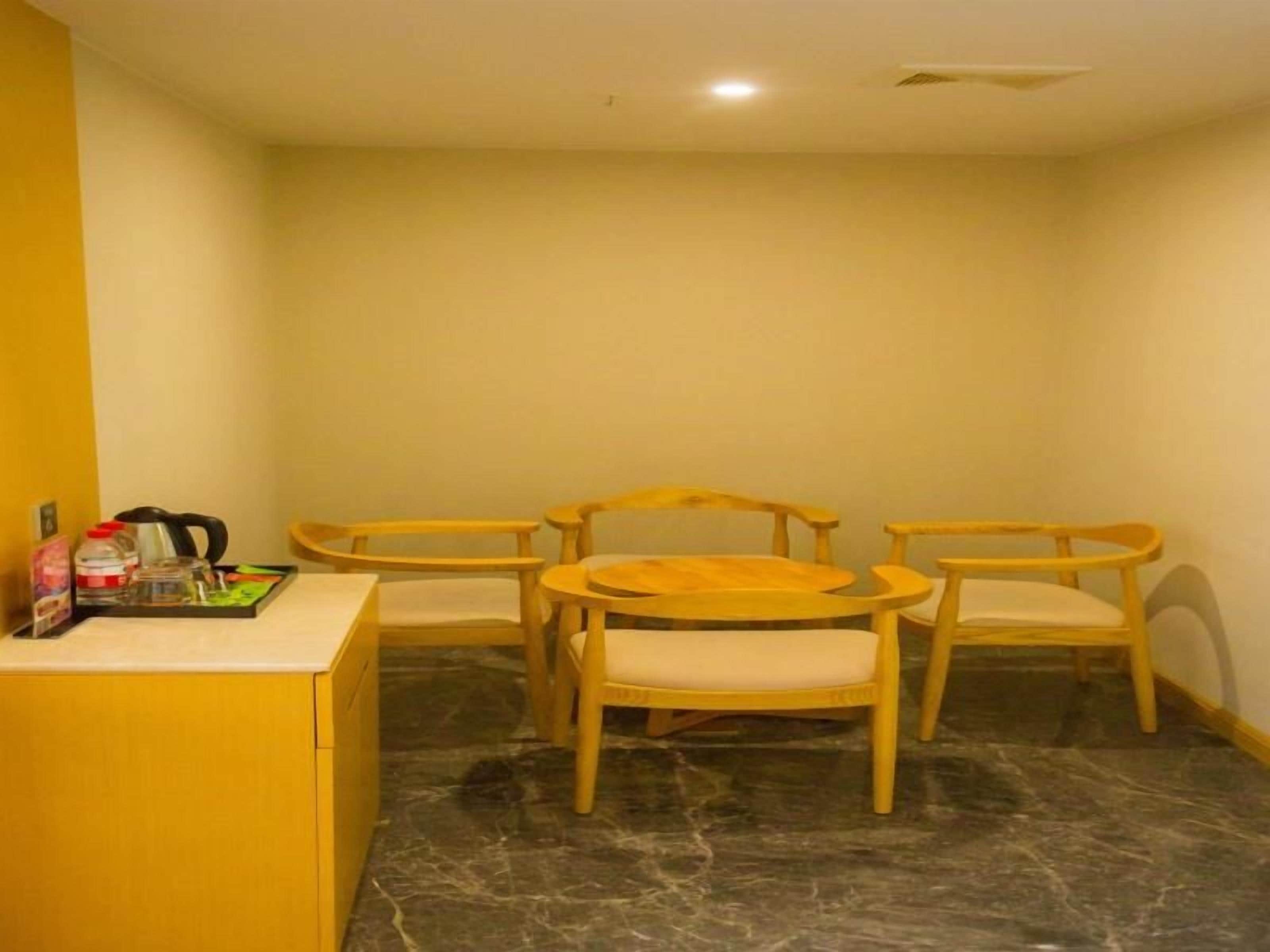 A room with a round table and four chairs, a small desk with a chair, and a tiled floor.